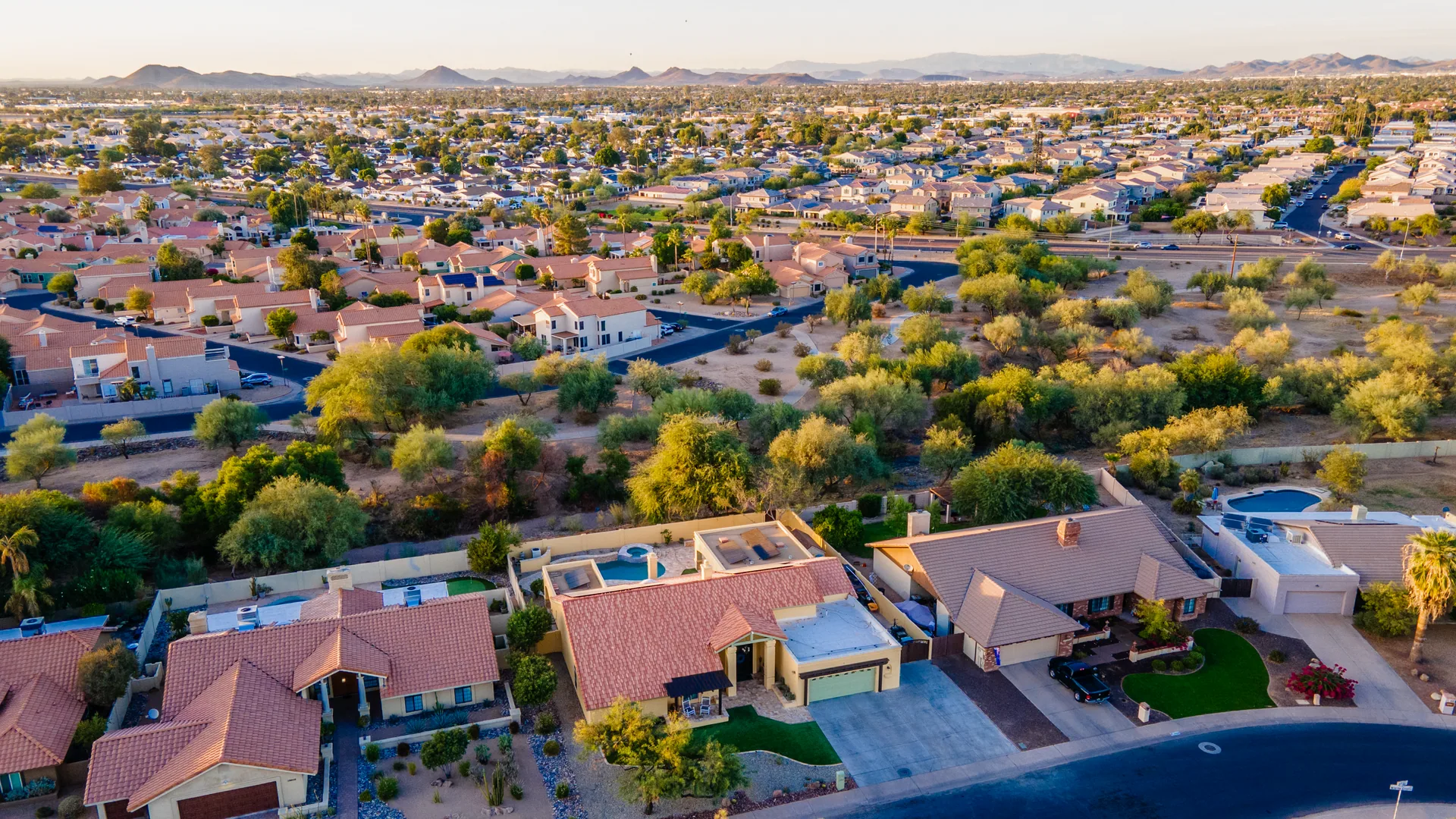 Aerial view of a Phoenix backyard with a pool and patio at golden hour