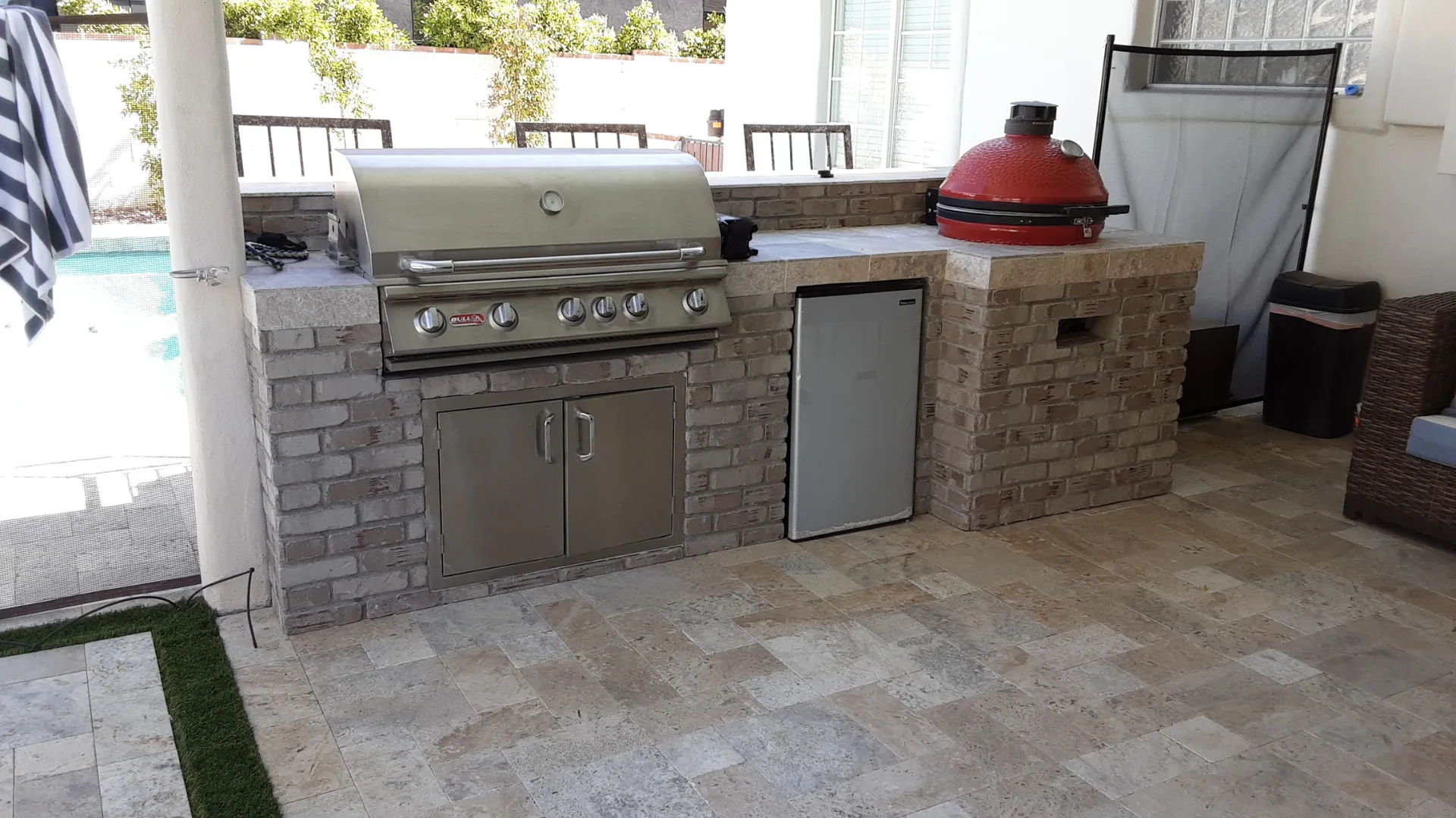 Brick grill island with a built-in grill, ceramic smoker, and refrigeration