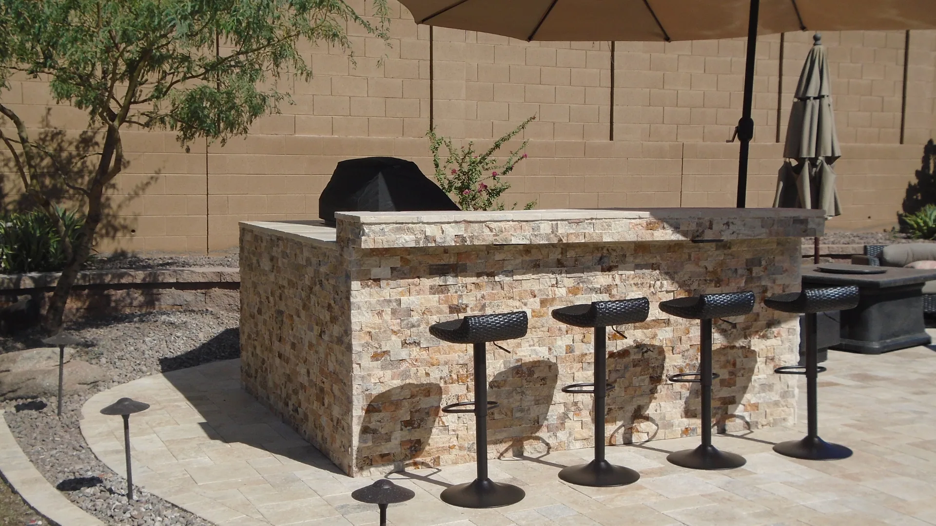 Outdoor bar island with stools on a travertine patio