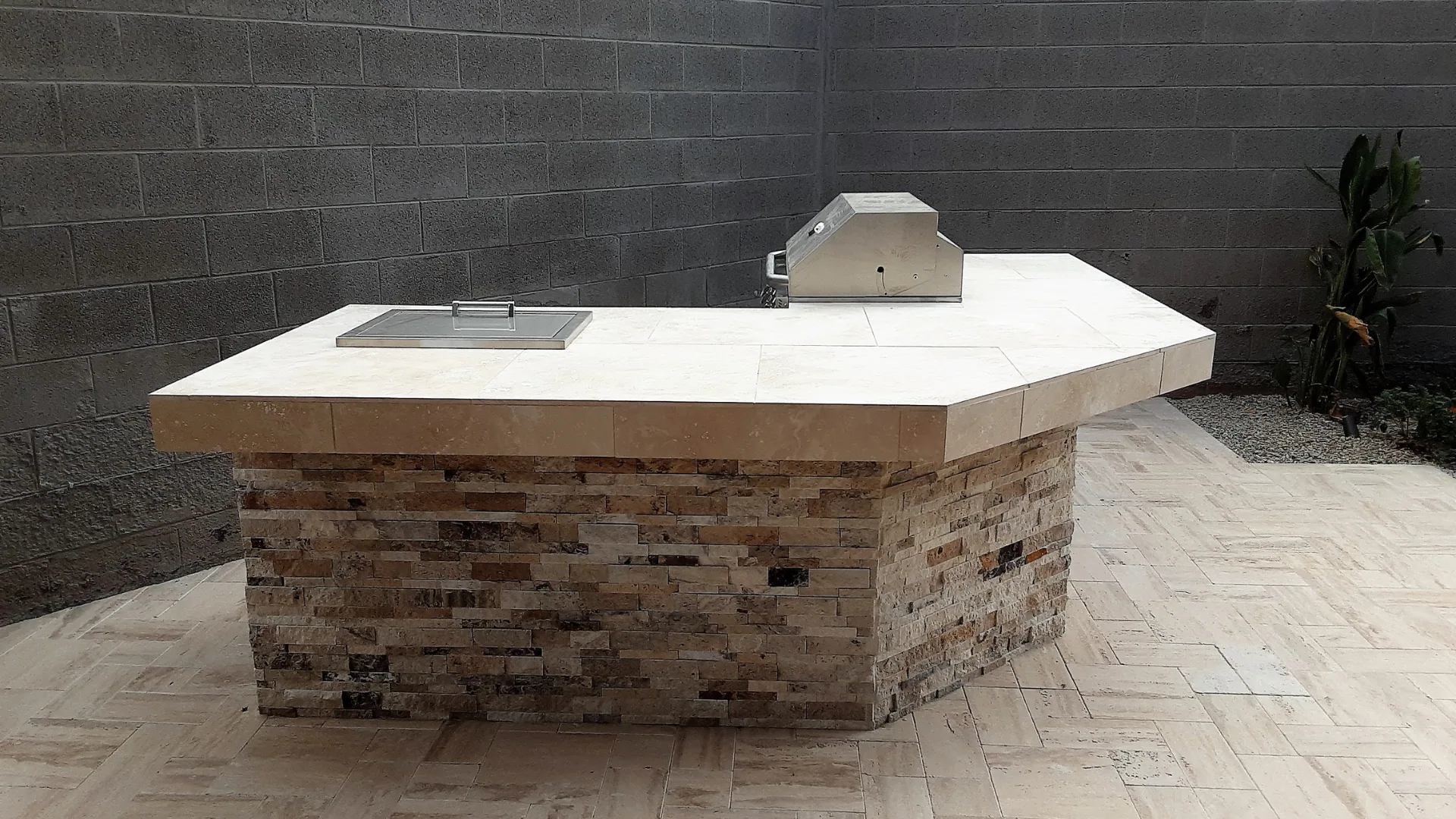 Stone-veneer grill island with a built-in grill and side burner