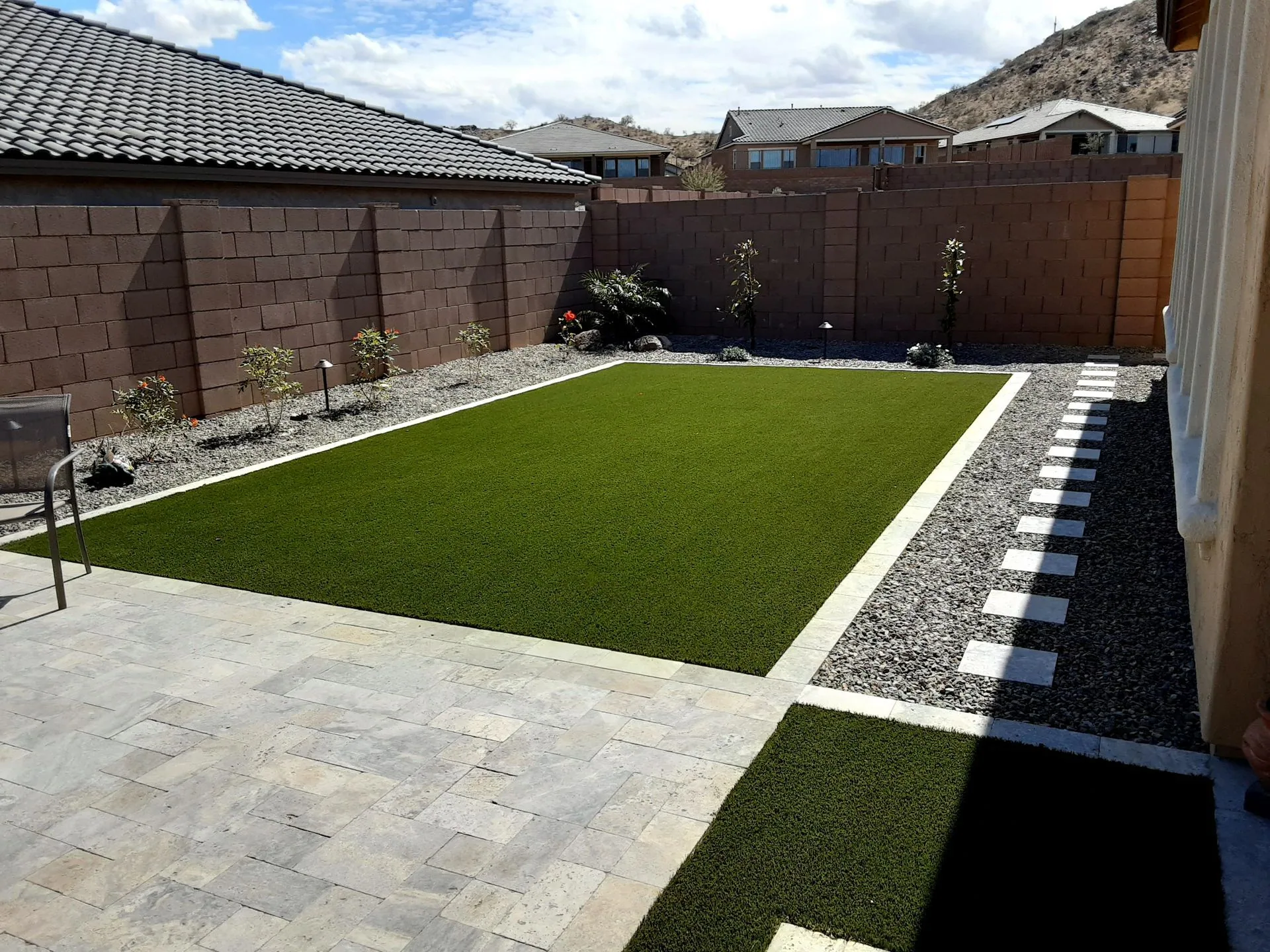 Travertine pavers, turf, and planting showing the finished material palette