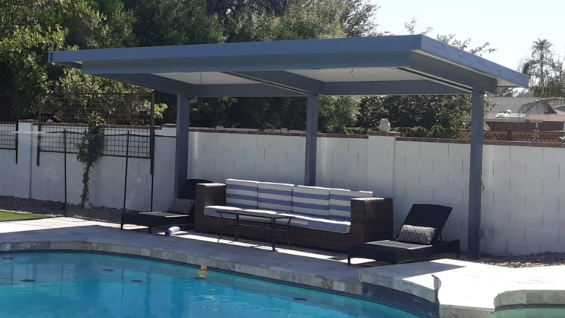 Cantilevered powder-coated metal shade structure beside a pool