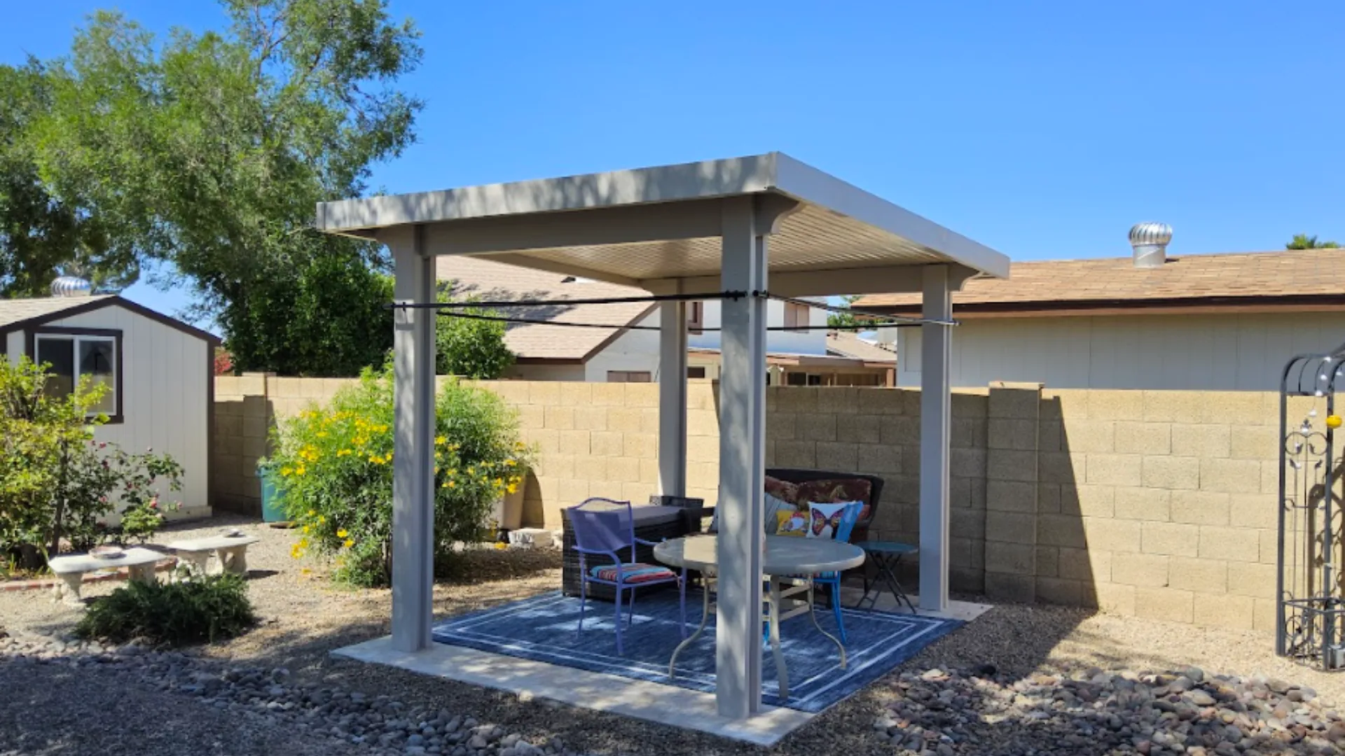 Freestanding metal shade structure over a small paver patio
