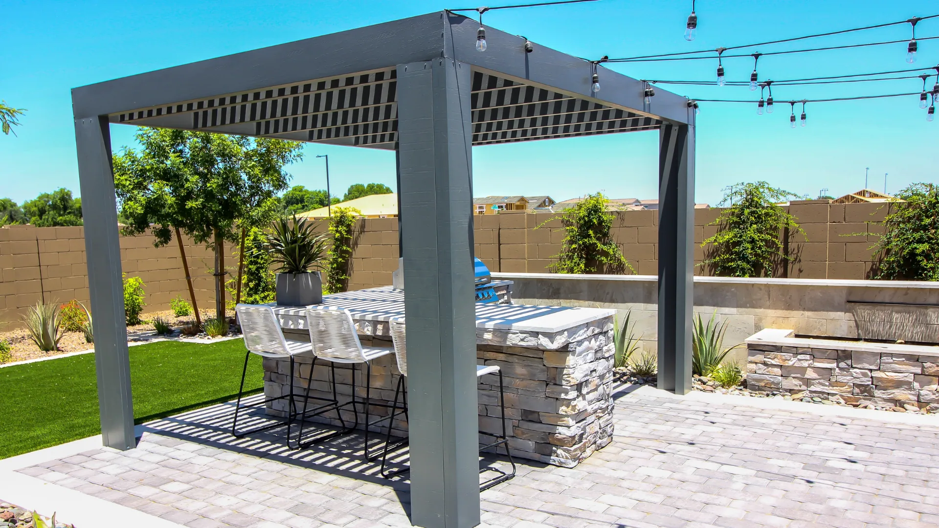 Metal pergola over a paver bar with stools and string lights