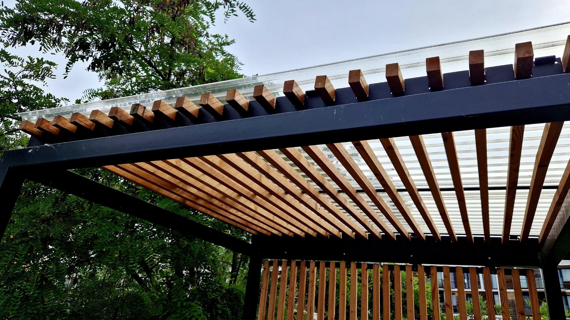 Wood-slat pergola roof with a polycarbonate cover