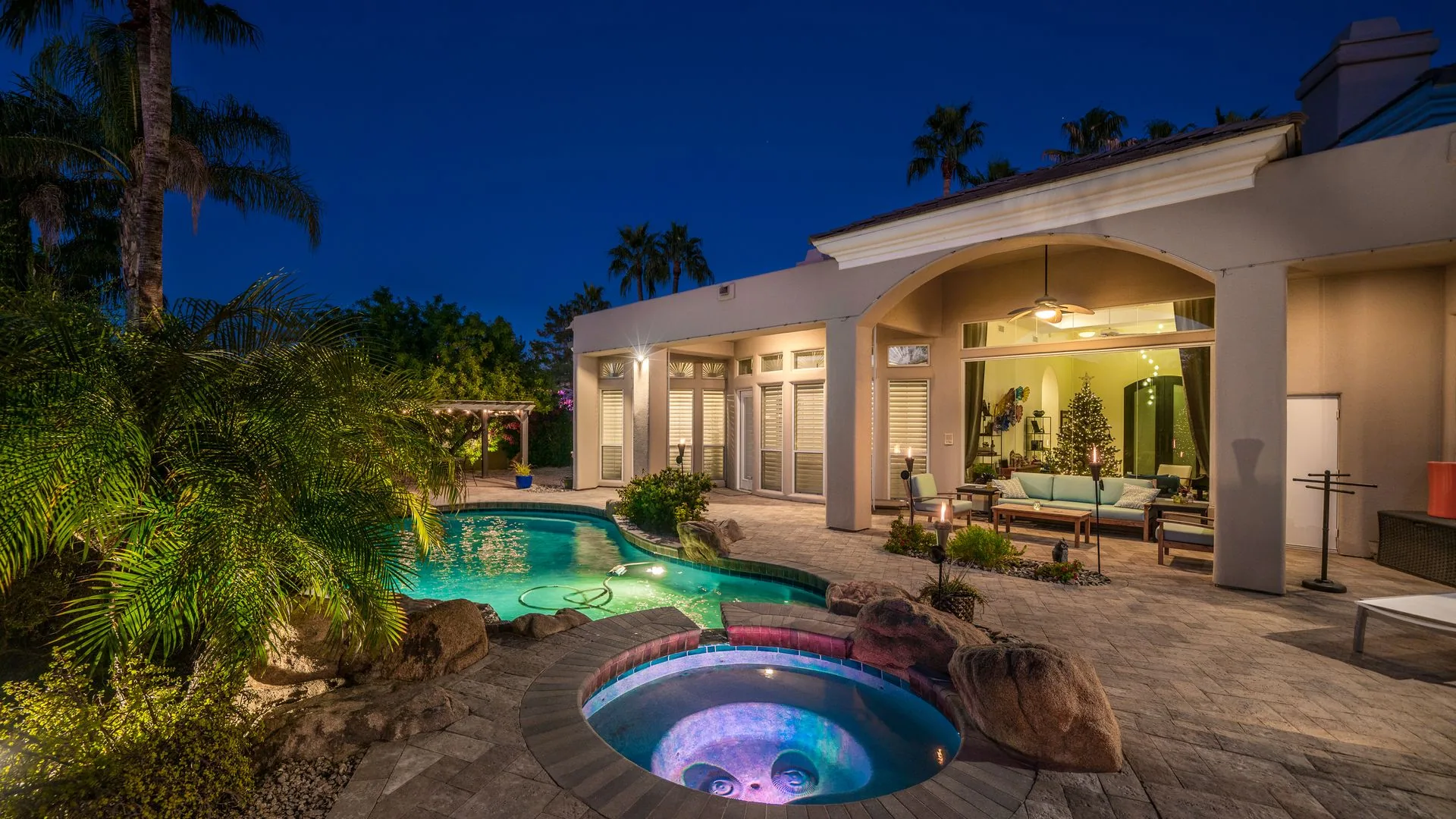Paver patio with pool and pergola at dusk
