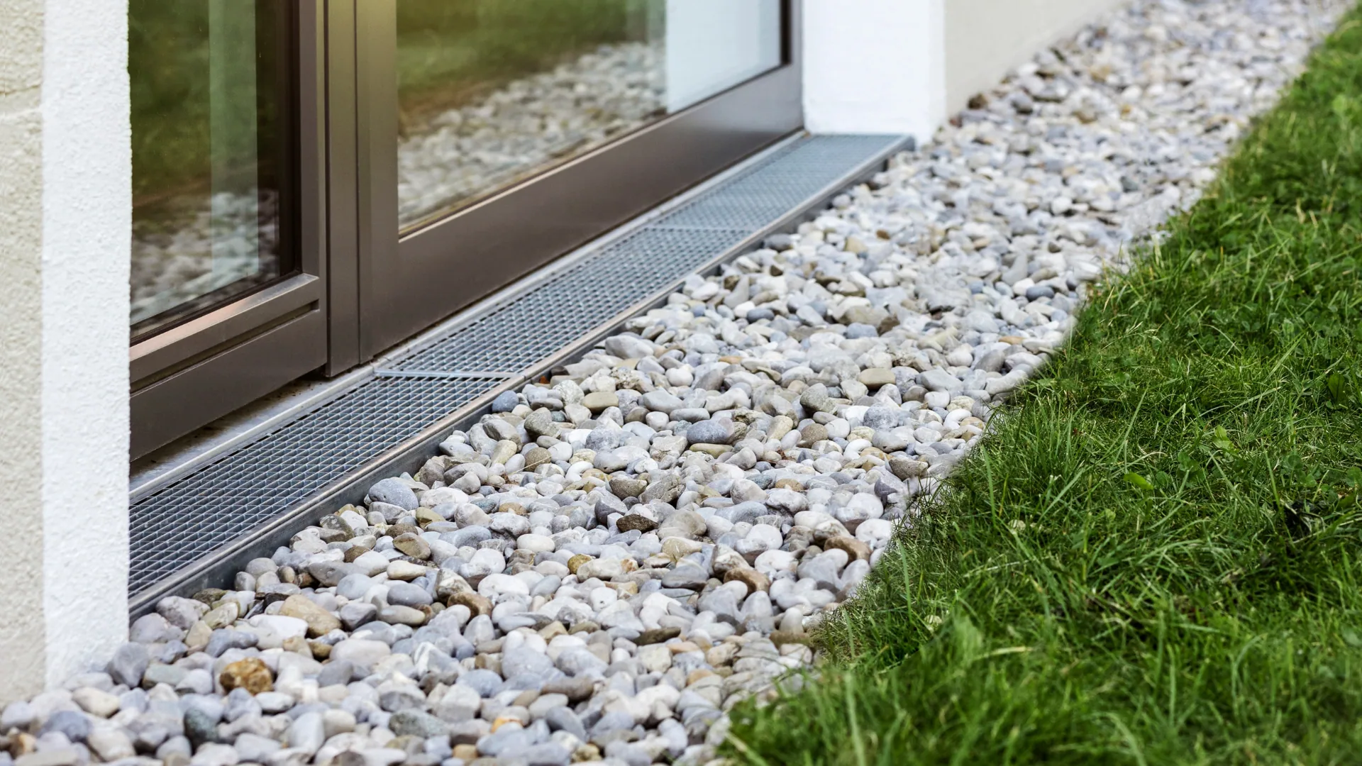 Decorative gravel border with a channel drain along a foundation