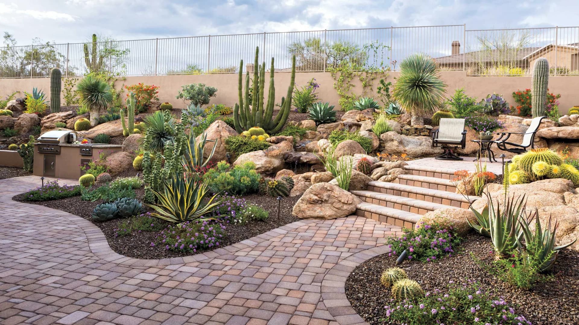 Desert rock garden with hand-set boulders, cacti, decorative granite, and paver steps