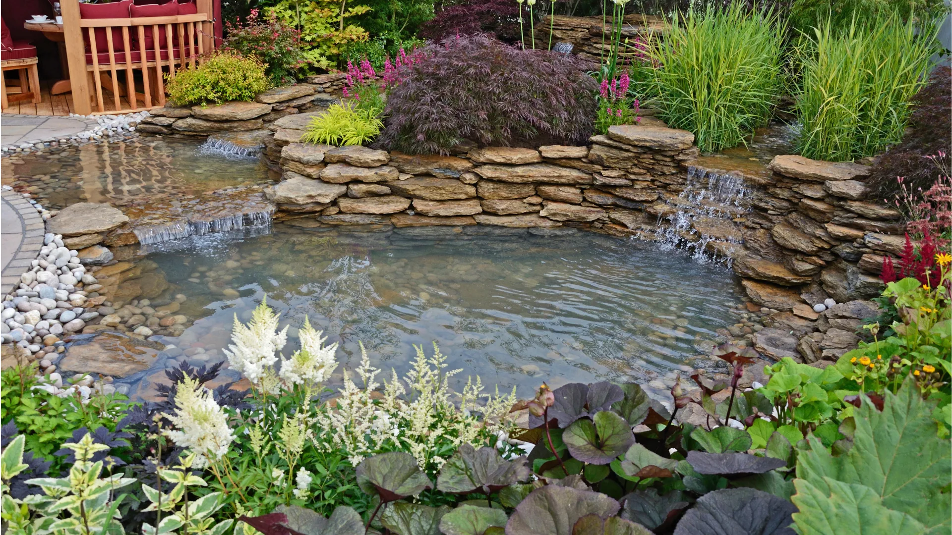 Natural pond with a stacked-stone waterfall and lush planting