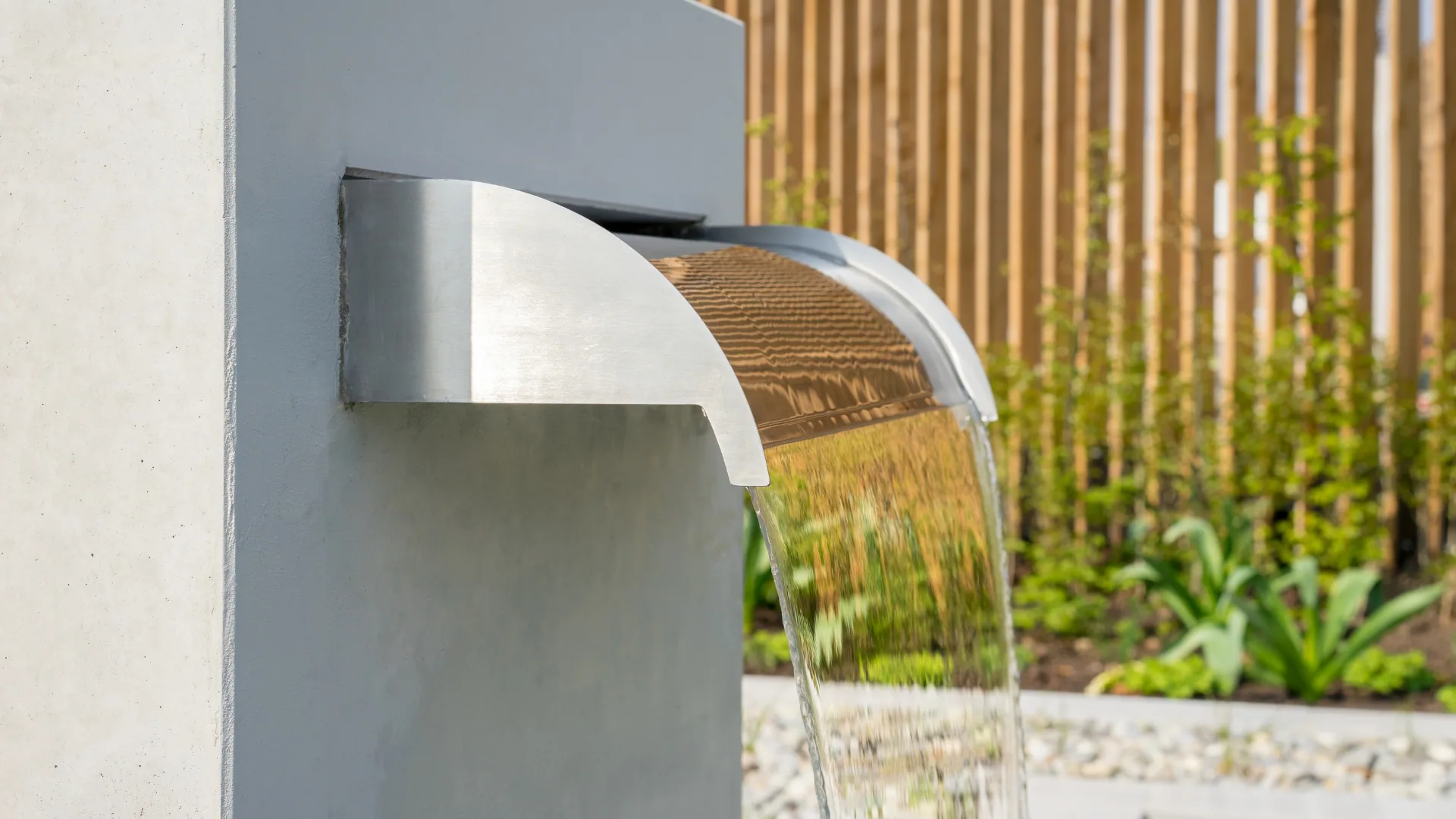 Stainless sheet-fall spillway cascading into a recirculating basin