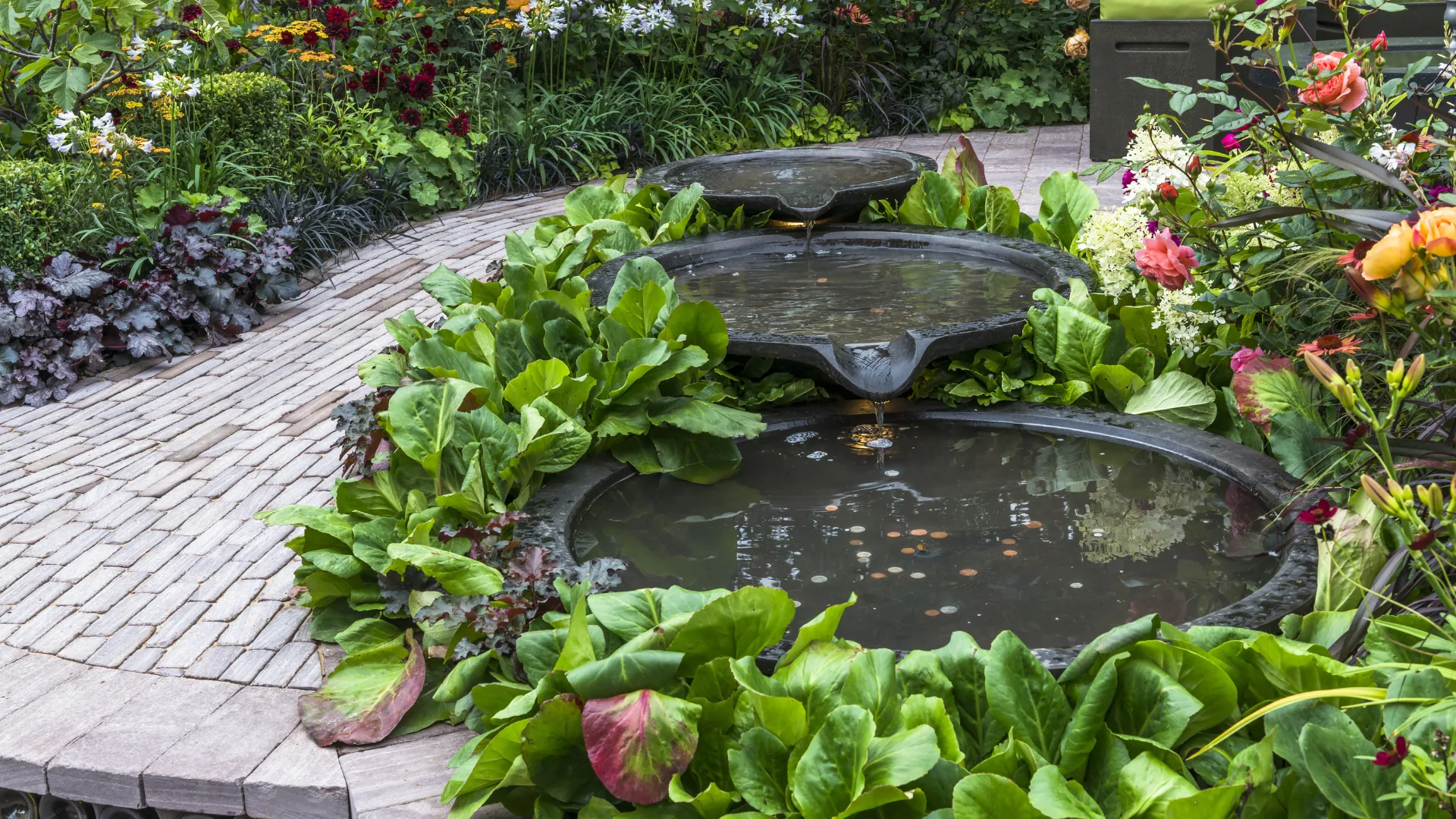 Stone bowl water garden surrounded by lush planting
